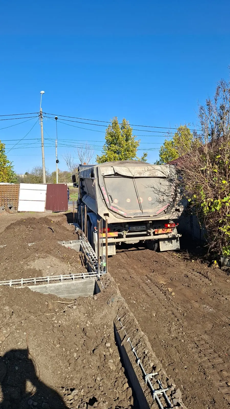 Săpătură de fundație finalizată, cu pereții tranșeei drepți și pământul evacuat lateral.