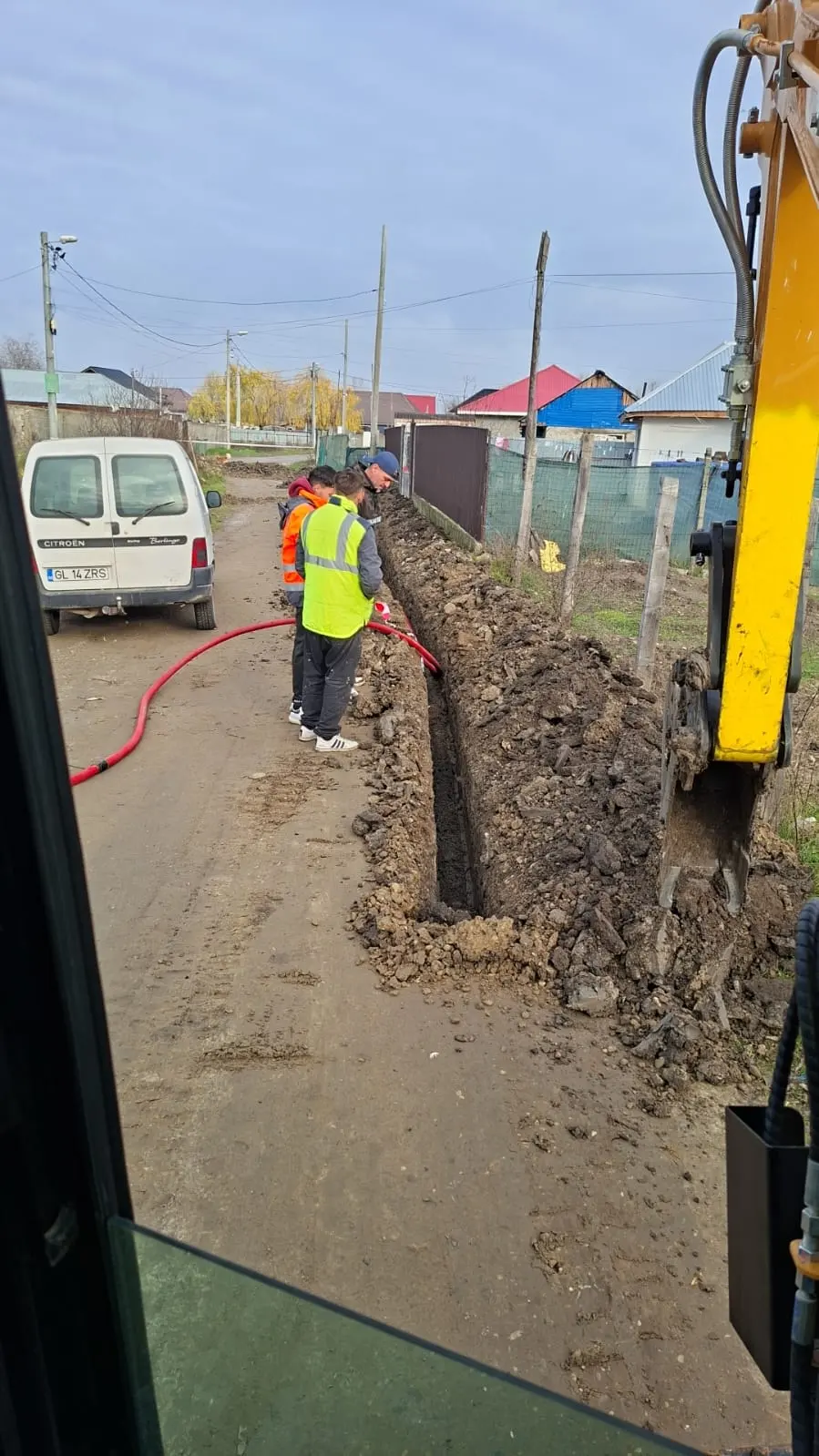 Traseu pentru cablu electric deschis în curte, cu pământul evacuat lateral.